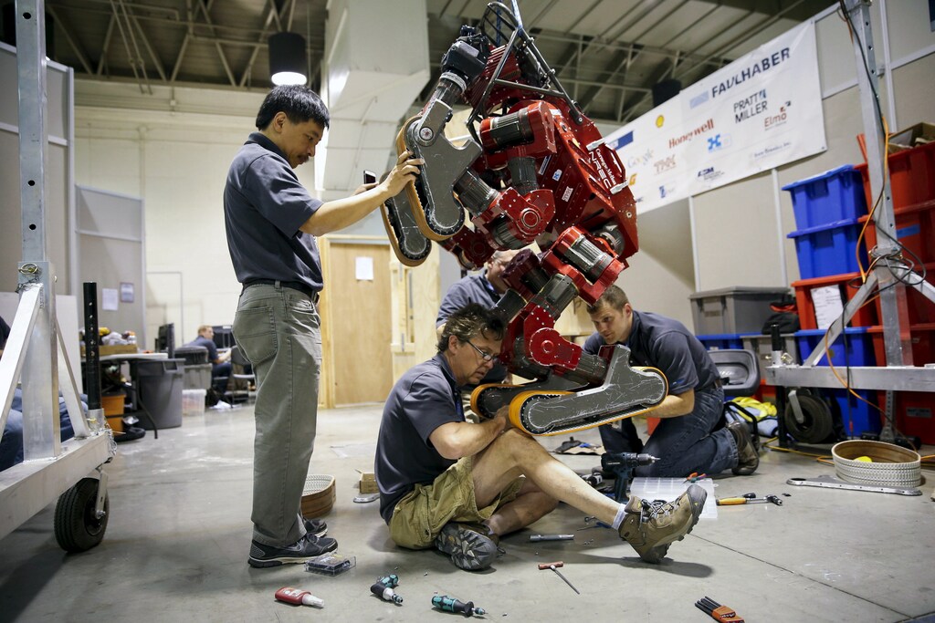 Mark Waldbaum (C) of Team Tartan Rescue CHIMP (CMU Highly Intelligent Mobile Platform) robot from Carnegie Mellon University has its tracks changed in the team garage during the finals of the Defense Advanced Research Projects Agency (DARPA) Robotic Challenge in Pomona, California June 6, 2015. Twenty-four teams are competing to win a portion of a $3.5 million prize by operating humanoid robots across a task and obstacle course. REUTERS/Patrick T. Fallon - GF10000119295