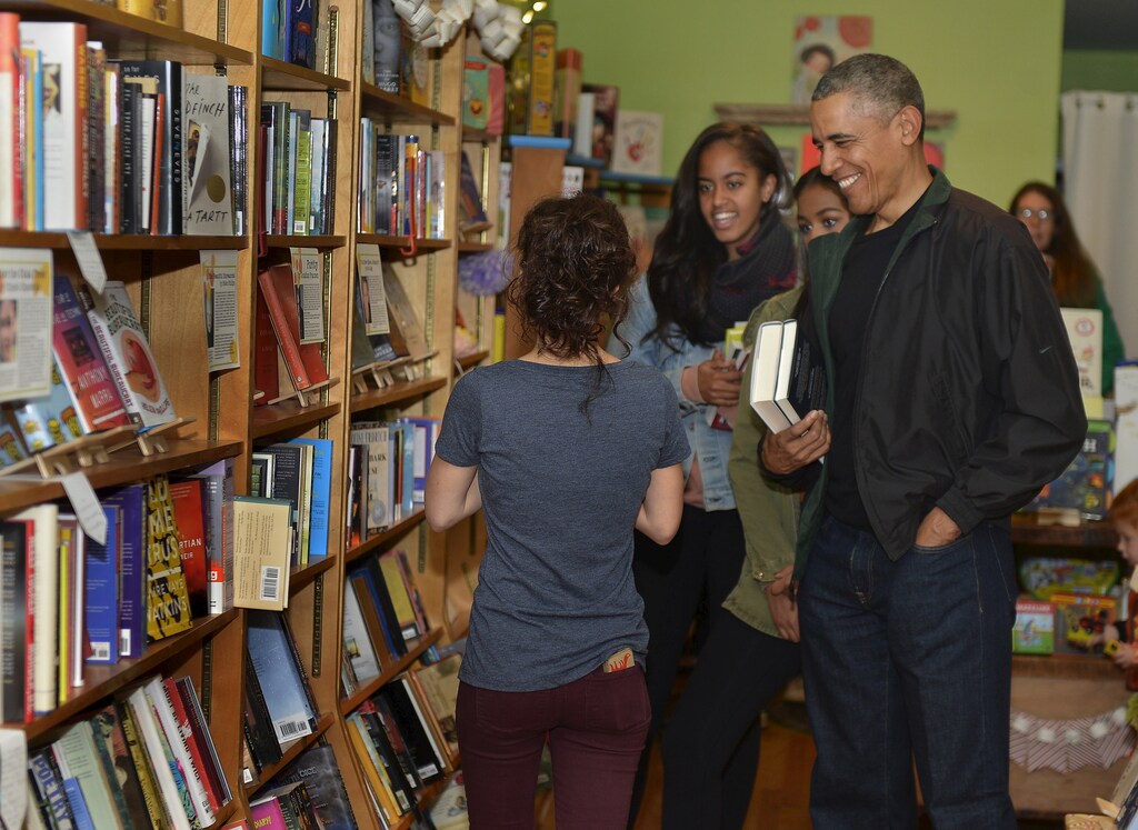 U.S. President Barack Obama (R) and his daughters Malia (C) and Sasha (partly hidden) interact with Upshur Street Books manager Anna Thorn as they buy books from the store in Washington, November 28, 2015. Today is Small Business Saturday, which was started to encourage shoppers to buy locally and from brick-and-mortar stores, and serves as a counterpoint to the traditionally busy shopping days of Black Friday and Cyber Monday after the Thanksgiving holiday. REUTERS/Mike Theiler - GF20000077754