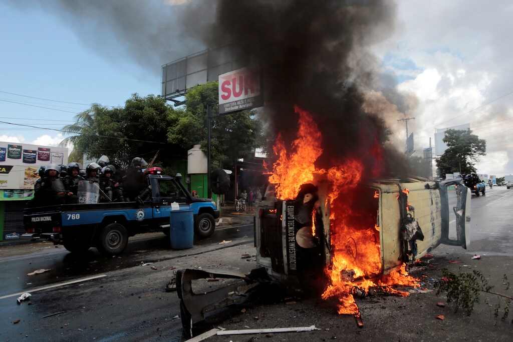 Riot police officers travel past a burning police car during a protest against Nicaraguan President Daniel Ortega's government in Managua, Nicaragua September 2, 2018.REUTERS/Oswaldo Rivas TPX IMAGES OF THE DAY - RC1CB8A23AC0