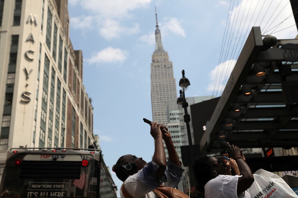 Women take photos of the solar eclipse along 34th street with iPhones outside Pennsylvania Station in Manhattan, New York, U.S., August 21, 2017. Location coordinates for this image are 40.7506° N, 73.9935° W. REUTERS/Shannon Stapleton - RC11E682DD10