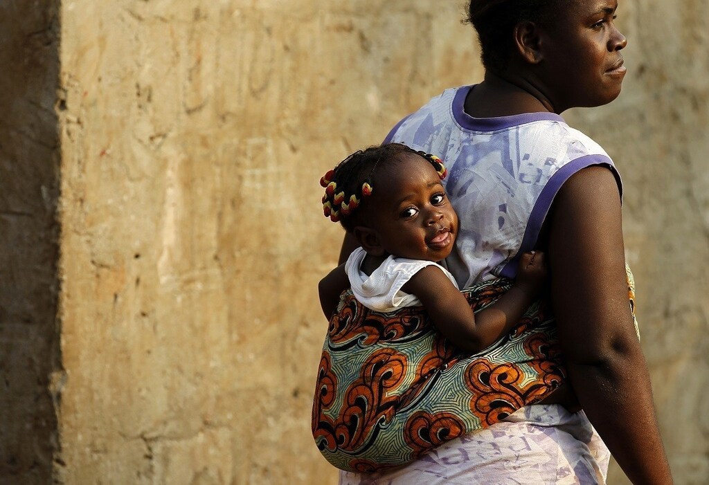 A woman with a baby on her back looks on at an informal settlement in the capital Luanda, August 30, 2012. Angolans will go to the polls on Friday to elect lawmakers and their president. REUTERS/Siphiwe Sibeko (ANGOLA - Tags: POLITICS ELECTIONS SOCIETY TPX IMAGES OF THE DAY) - RTR37ADK