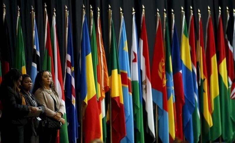 Women stand in front of some of the flags representing the 54 sovereign states that are members of the AU, at the end of the 25th African Union summit in Johannesburg, June 15, 2015. REUTERS/Siphiwe Sibeko - RTX1GN64