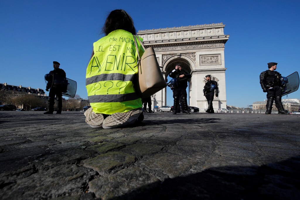 A protester wearing a yellow vest kneels on the Champs Elysees near the Arc de Triomphe during a demonstration by the "yellow vests" movement in Paris, France, February 23, 2019. Message reads, "Mr Macron, What is my Future". REUTERS/Philippe Wojazer TPX IMAGES OF THE DAY - RC1A56F17E90