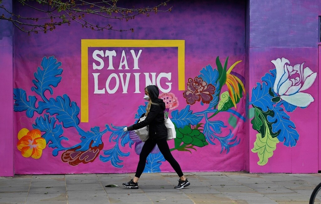 A woman wearing a protective face mask and gloves is seen walking past a mural, following the outbreak of the coronavirus disease (COVID-19), London, Britain, May 11, 2020. REUTERS/Dylan Martinez - RC2EMG9RRWMR