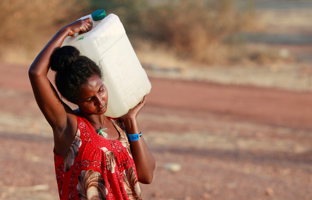 a woman carries a container of water