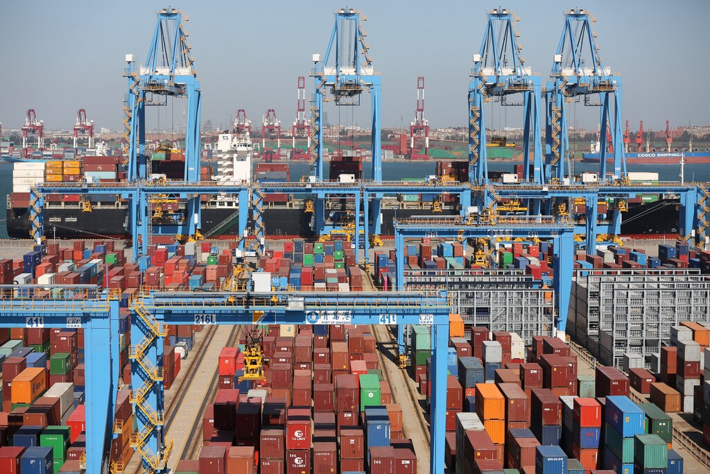 A cargo ship is seen behind containers at an automated container terminal in Qingdao port, Shandong province, China October 1, 2018. Picture taken October 1, 2018. REUTERS/Stringer ATTENTION EDITORS - THIS IMAGE WAS PROVIDED BY A THIRD PARTY. CHINA OUT. - RC12634E95E0