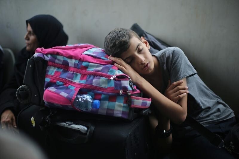 A Palestinian boy sleeps as he waits with his family for a travel permit to cross into Egypt through the Rafah border crossing after it was opened by Egyptian authorities for humanitarian cases, in Rafah in the southern Gaza Strip August 16, 2017. REUTERS/Ibraheem Abu Mustafa - RC121081F420