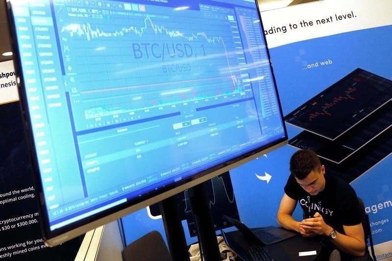 A man works beneath a display showing the market price of Bitcoin on the floor of the Consensus 2018 blockchain technology conference in New York City, New York, U.S., May 16, 2018. REUTERS/Mike Segar - RC17E3576990