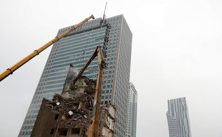 An excavator demolishes a building near skyscrapers in the centre of Warsaw, Poland November 9, 2017. Picture taken November 9, 2017. REUTERS/Kacper Pempel
