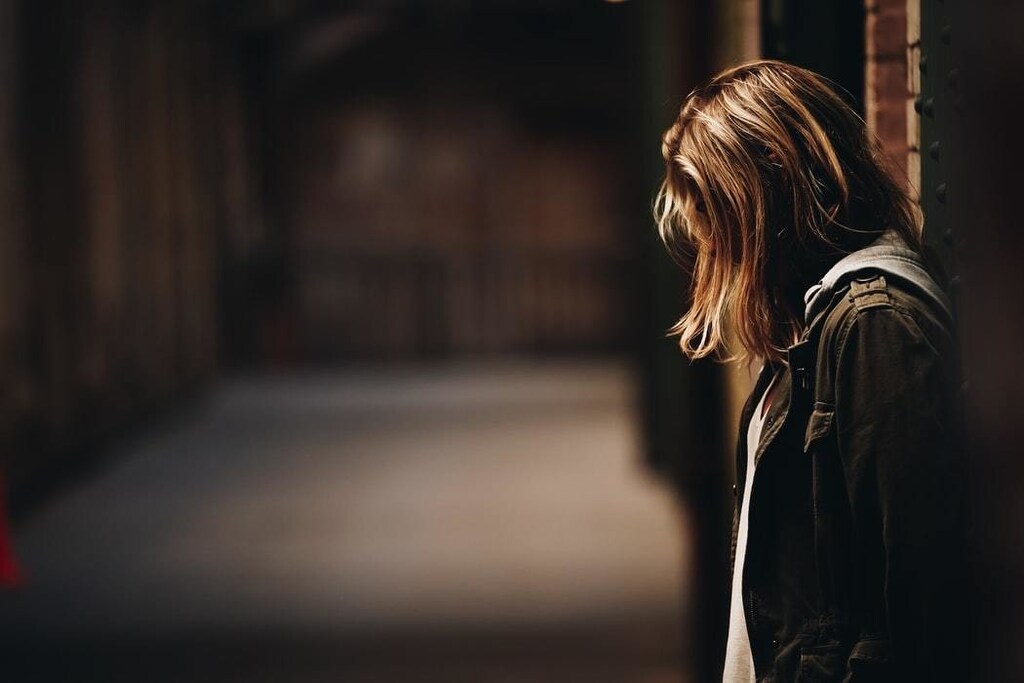 A girl stands in a dimly lit hallway.