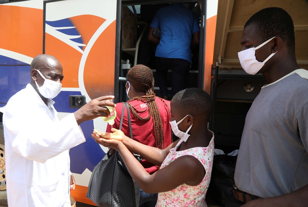 A health worker puts hydroalcoholic gel on the hands of a pupil as she boards a government chartered bus convoy, which will take students and teachers back to cities and schools of the countryside, as the lockdown due to coronavirus disease (COVID-19) is eased, in Abidjan, Ivory Coast May 19, 2020. Picture taken May 19, 2020. REUTERS/Luc Gnago - RC2PVG9294A5