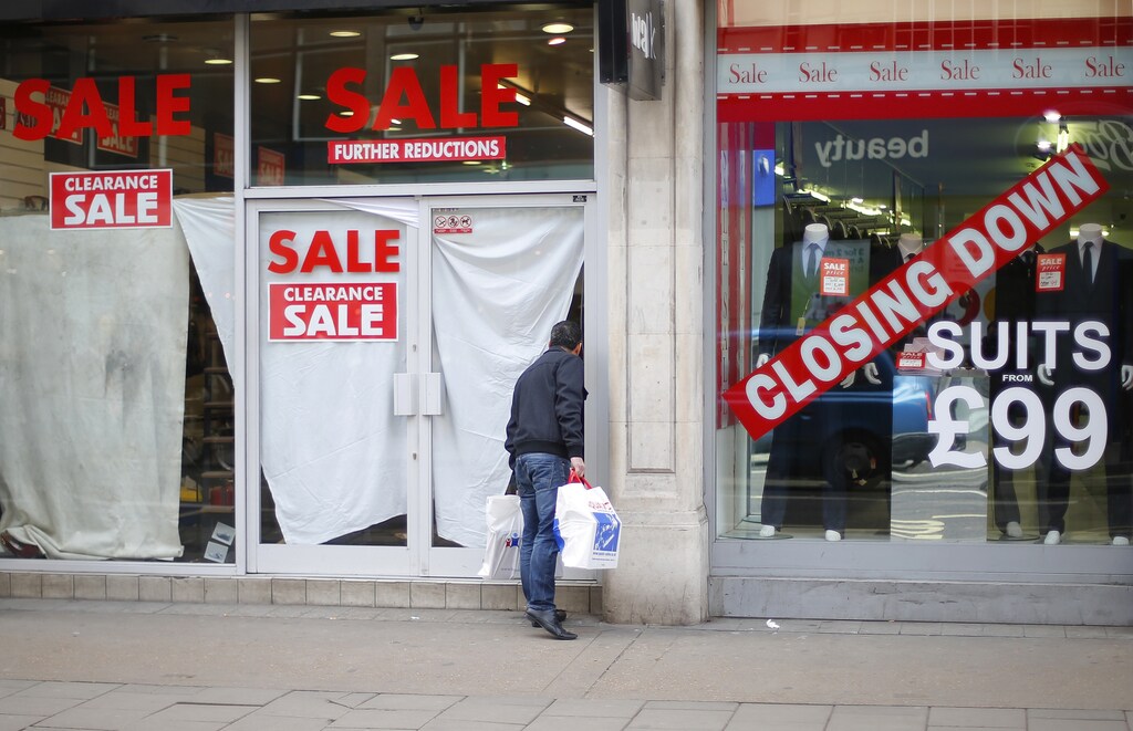 A man peers into a closed down shop, next door to another shop holding a closing down sale, in central London February 27, 2013. Britain's economy contracted by 0.3 percent in the last quarter of 2012 as first thought, keeping alive the danger of a third recession since 2008, although yearly growth was revised up, data showed on Wednesday. REUTERS/Andrew Winning (BRITAIN - Tags: POLITICS BUSINESS) - LM1E92R1CFH01