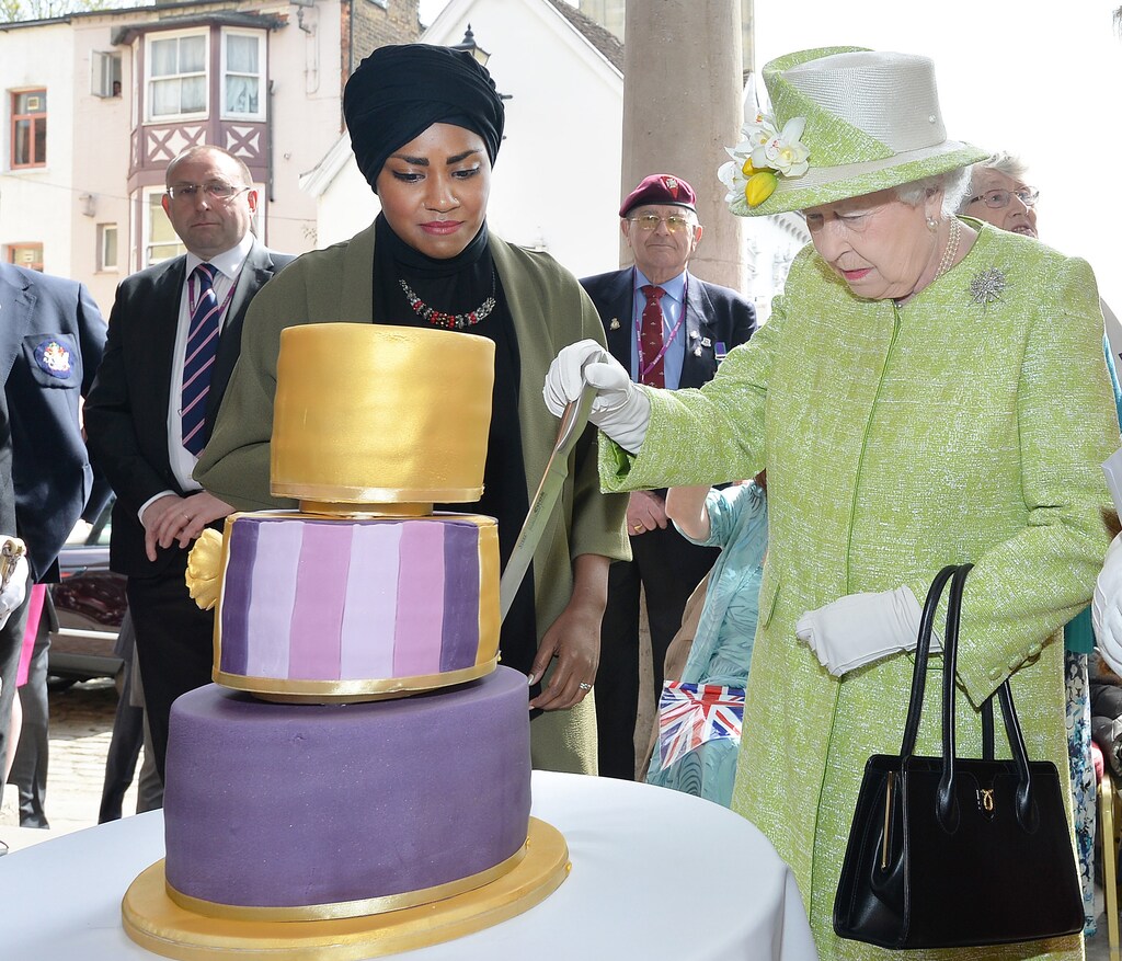 Britain's Queen Elizabeth cuts the cake Nadiya Hussain, winner of the Great British Bake Off baked for her, as she walks through Windsor on her 90th Birthday, in Windsor, Britain April 21, 2016. REUTERS/John Stillwell/Pool - LR1EC4L11IFFY