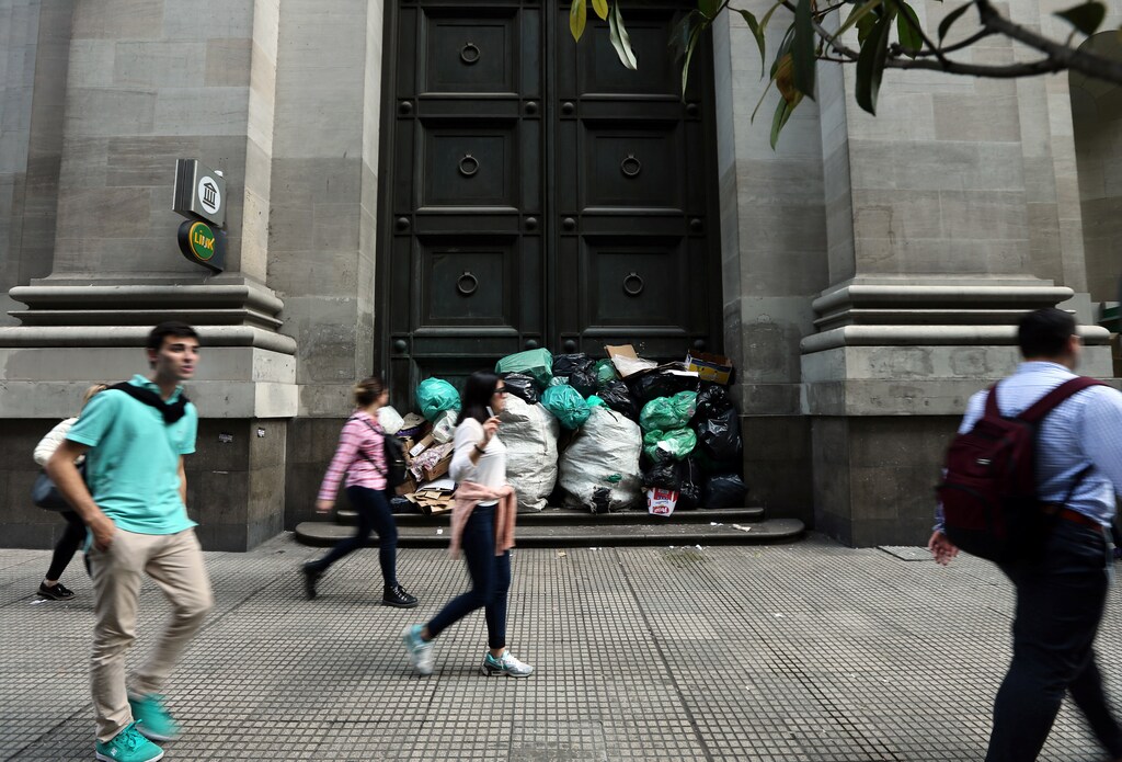 People walk past rubbish bags piled up at the entrance of a bank in Buenos Aires' financial district, Argentina September 1, 2017. REUTERS/Marcos Brindicci - RC14E83FB720