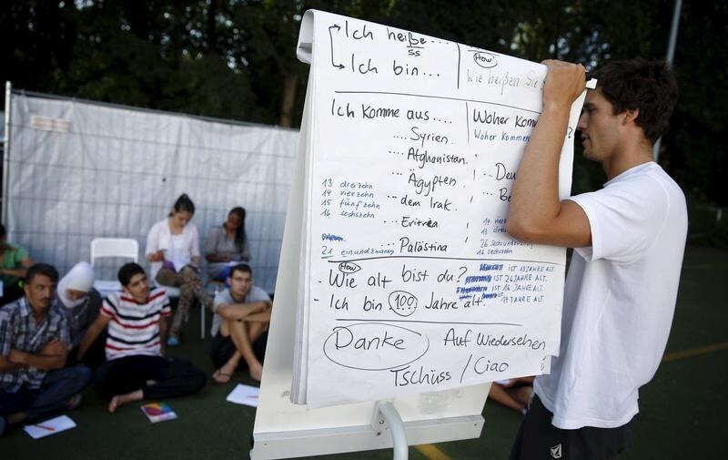 A volunteer gives German language instruction to asylum seekers at an emergency reception centre for asylum seekers in Berlin's district Moabit, Germany, August 3, 2015.