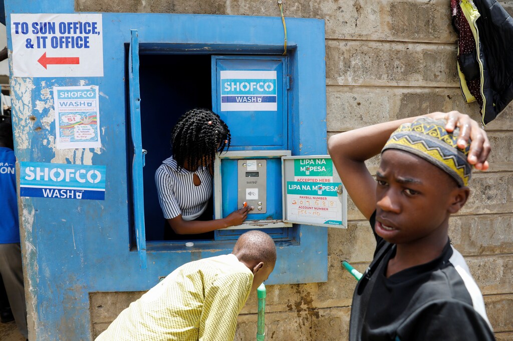 An employe of community organisation Shining Hope for Communities (SHOFCO) activates a water selling machine at a in the Kibera slum in Nairobi, Kenya, March 18, 2020.