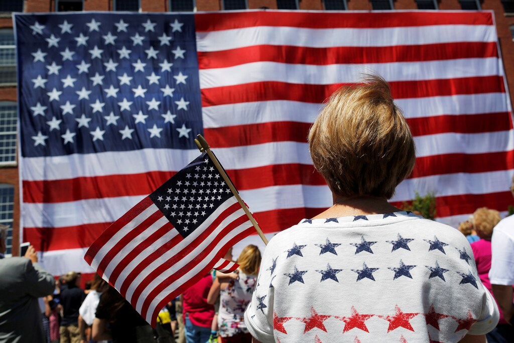 Onlookers watch as a 95-by-50-foot American flag is unfurled on the side of an apartment complex, a replica of the "The Great Flag" that was spun, woven, dyed, constructed and displayed on the same building by Amoskeag Manufacturing Company in 1914, in Manchester, New Hampshire, U.S., June 14, 2017. REUTERS/Brian Snyder - RC181DACF0B0