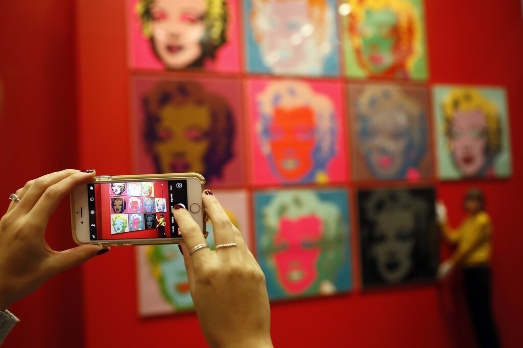 A woman takes a photograph with her mobile phone of ten screenprints of Marilyn Monroe by Andy Warhol as part of the exhibition "American Dream: pop to the present" at the British Museum in London, Britain February 10, 2017. REUTERS/Stefan Wermuth - LR1ED2A0SD900