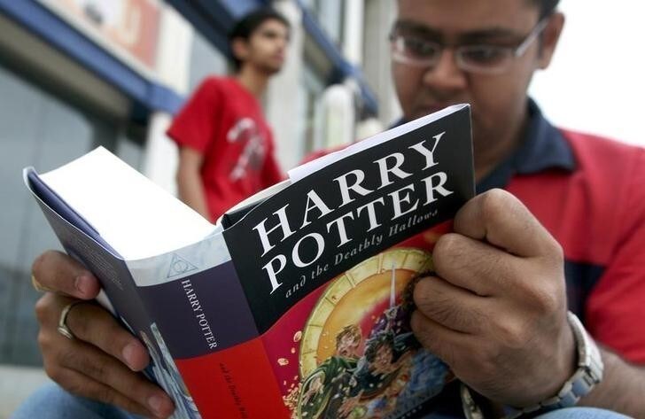 A fan reads the new "Harry Potter and the Deathly Hallows" by J.K. Rowling as he sits outside a bookstore in the western Indian city of Ahmedabad July 21, 2007. Harry Potter fans poured into book stores around the world on Saturday to get hold of the seventh and final volume in the series and discover the secret of the boy wizard's fate. REUTERS/Amit Dave (INDIA)
