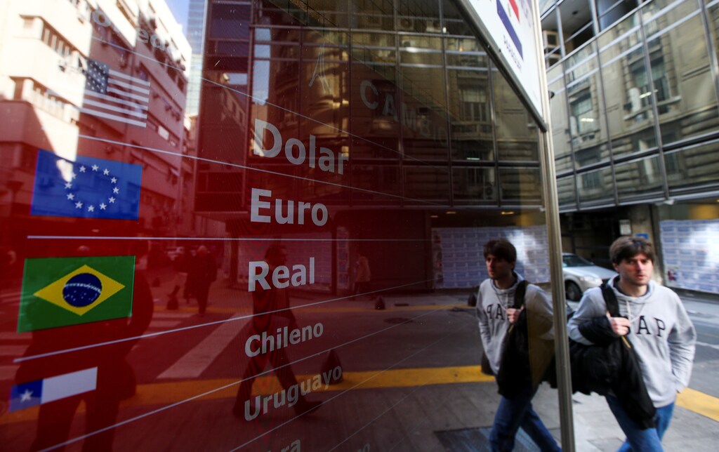 A man walks past an electronic board showing currency exchange rates, in Buenos Aires, Argentina August 20, 2019. REUTERS/Agustin Marcarian - RC17EF451D70
