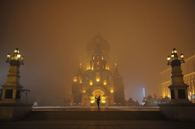 A person takes pictures in smog at the square in front of a church in Harbin, Heilongjiang province, November 10, 2015. Picture taken November 10, 2015. REUTERS/Stringer CHINA OUT. NO COMMERCIAL OR EDITORIAL SALES IN CHINA TPX IMAGES OF THE DAY - RTS6F3Y