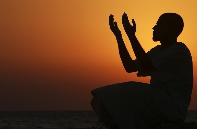A man raises his hands to pray near the sea at sunset after a day of fasting in the holy month of Ramadan in Benghazi July 24, 2012. Picture taken July 24, 2012. REUTERS/Esam Al-Fetori (LIBYA - Tags: RELIGION SOCIETY TPX IMAGES OF THE DAY) - RTR35A9L