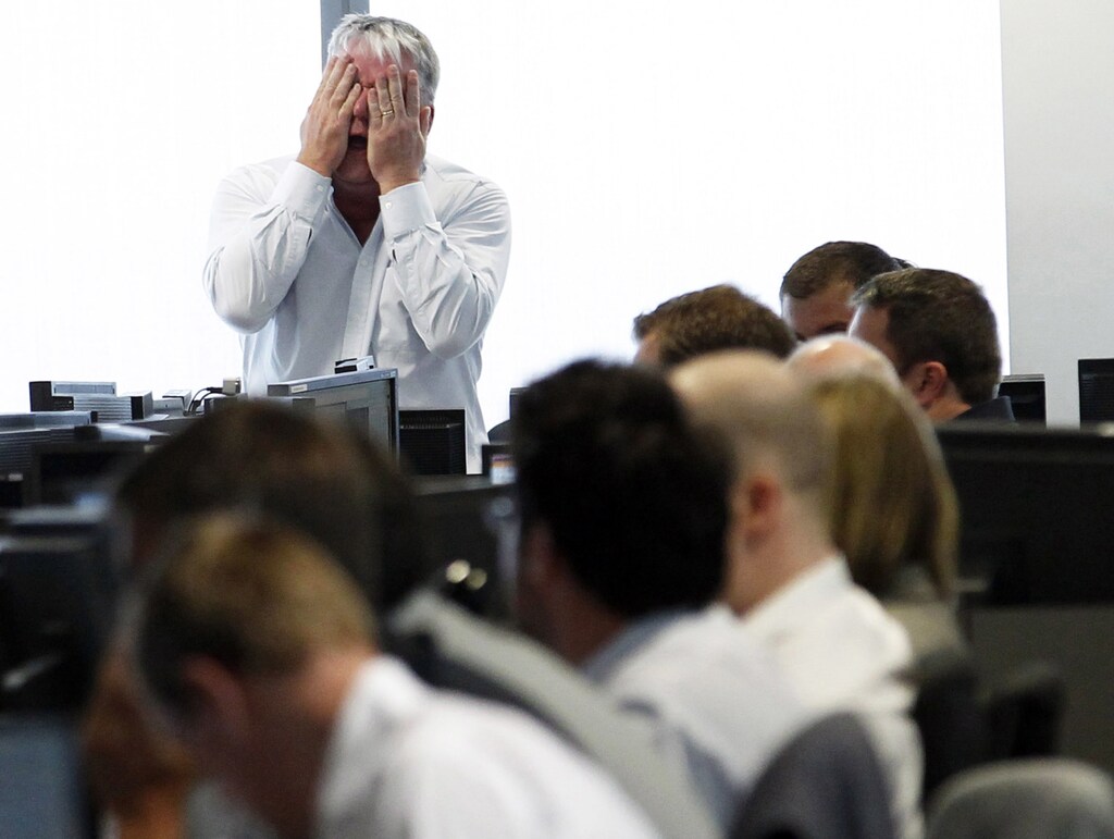 A broker reacts at BGC Partners at Canary Wharf financial district in London August 5, 2011. Banks and commodity stocks fell sharply on Friday as Britain's top share index extended losses into a sixth straight trading day, roiled by a global debt crisis and unmoved by U.S. jobs data easing fears of another economic recession. London's blue chip index closed down 146.15 points, or 2.7 percent at 5,246.99, as investors continued to pile funds into safer havens such as bonds, gold and the Swiss franc. REUTERS/Luke MacGregor (BRITAIN - Tags: BUSINESS IMAGES OF THE DAY) - GM1E78603KS01