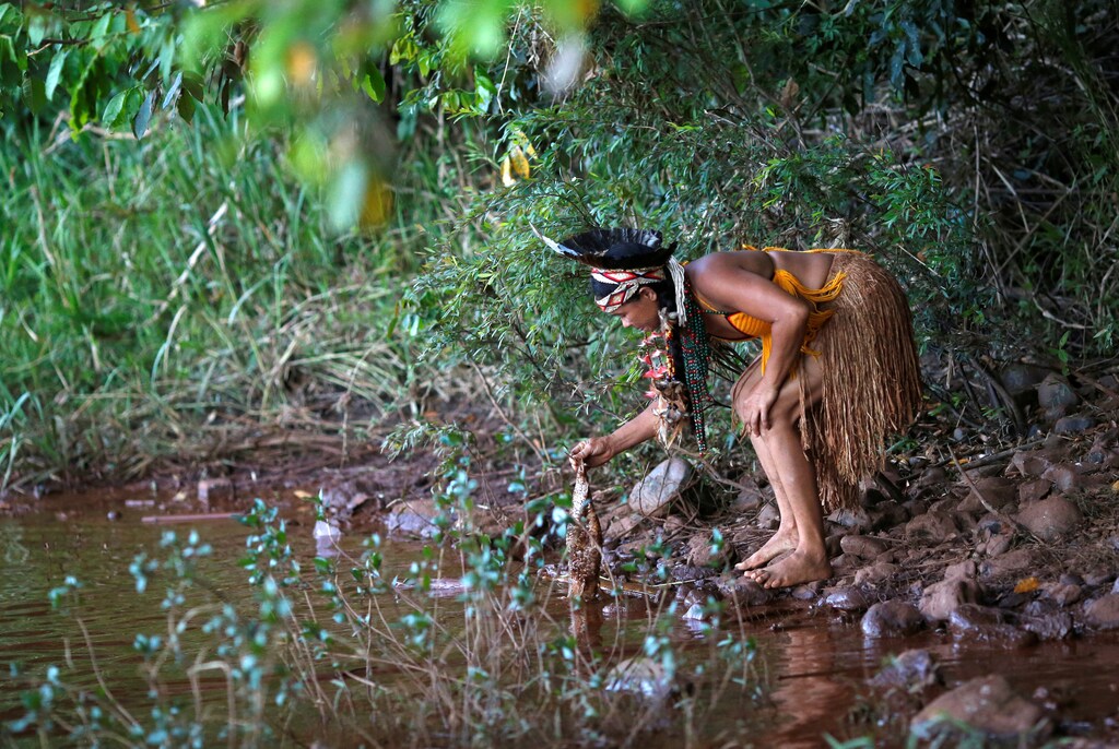 An Indigenous woman from the Pataxo Ha-ha-hae tribe holds up a dead fish near Paraopeba river