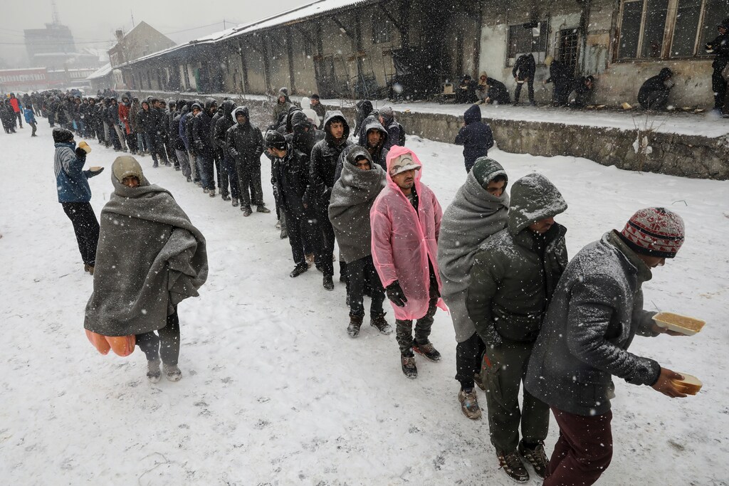Migrants stand in line to receive free food outside a derelict customs warehouse in Belgrade, Serbia January 9, 2017.