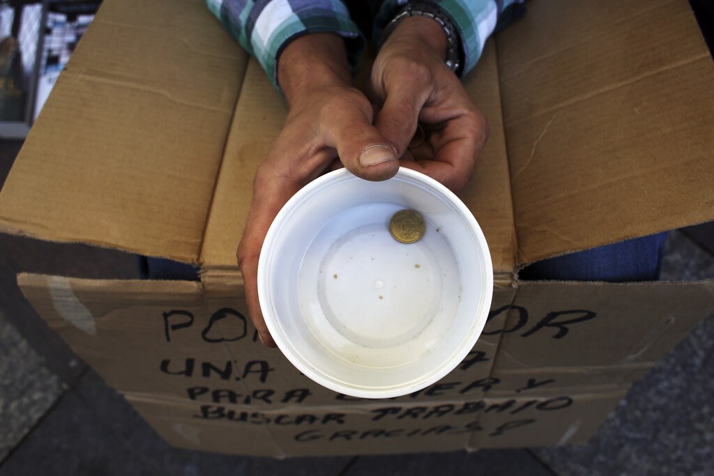 A beggar holds a plastic cup as he asks for money in central Madrid, October 10, 2013. Beggars, dog-lovers and fortune-tellers who venture onto Madrid's busy streets may soon find themselves out of pocket as authorities in the city and elsewhere seek creative solutions to their financial problems.The Madrid council laid out plans this week to levy fines of 750 euros ($1,000) for public activities including soliciting for money outside shopping centres, feeding or washing dogs, reading tarot cards and performing acrobatics with a bike. Saddled with huge debts since a property bubble burst in 2008, Spain's autonomous regions and town halls have seen core revenues fall as unemployment holds stubbornly above 25 percent and corporate investments dry up. Many owe millions to service suppliers and staff. REUTERS/Susana Vera (SPAIN - Tags: POLITICS BUSINESS SOCIETY POVERTY) - GM1E9AA1PL501