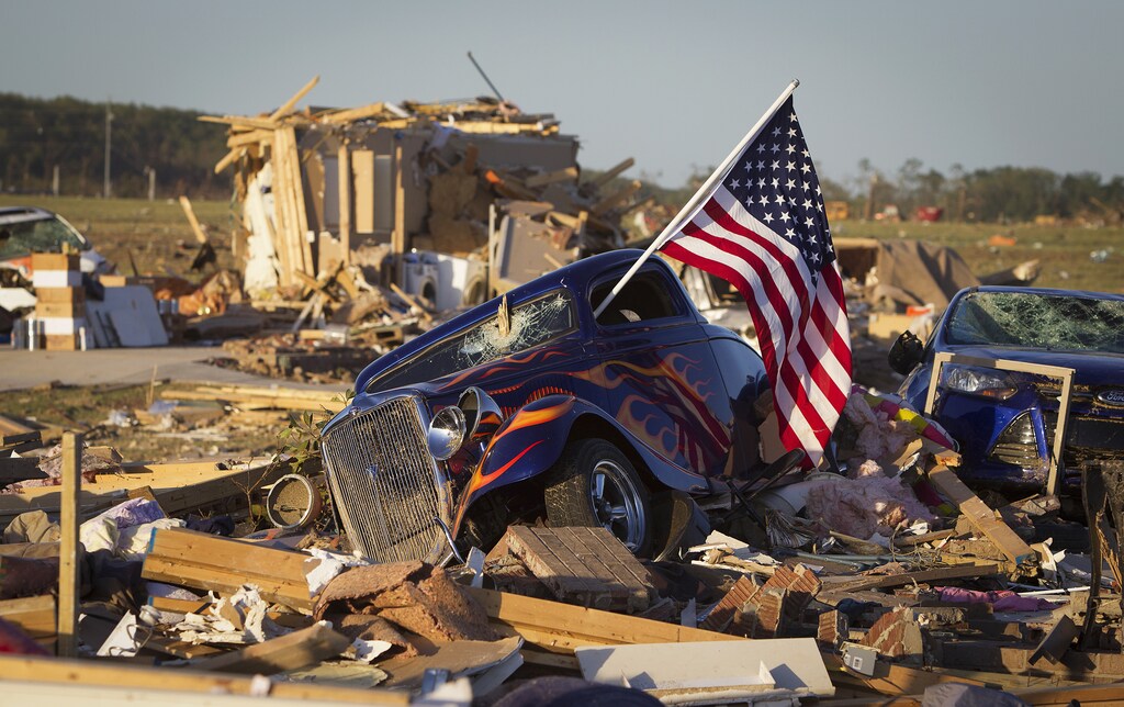 A U.S. flag sticks out the window of a damaged hot rod car in a suburban area after a tornado near Vilonia, Arkansas April 28, 2014. On a second day of ferocious storms that have claimed at least 19 lives in the southern United States, a tornado tore through the Mississippi town of Tupelo on Monday causing widespread destruction to homes and businesses, according to witnesses and local emergency officials. Most of the deaths from the violent storms occurred on Sunday when tornadoes tossed cars like toys in Arkansas and other states. REUTERS/Carlo Allegri (UNITED STATES - Tags: DISASTER ENVIRONMENT TPX IMAGES OF THE DAY) - GM1EA4T0R6Z01
