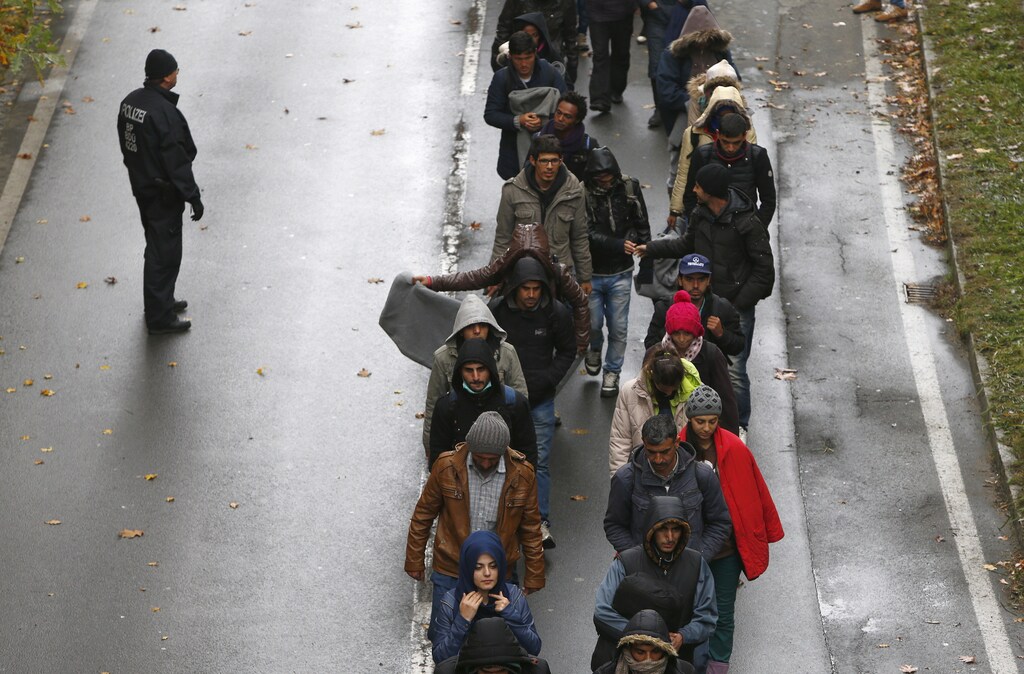 Migrants walk along a street after crossing the Austrian-German border from Achleiten, Austria, in Passau, Germany, October 29, 2015. German Chancellor Angela Merkel came under intense pressure for her handling of the refugee crisis on Wednesday, with her Bavarian allies warning of a full-blown coalition crisis unless she takes immediate action to limit a record influx of migrants.