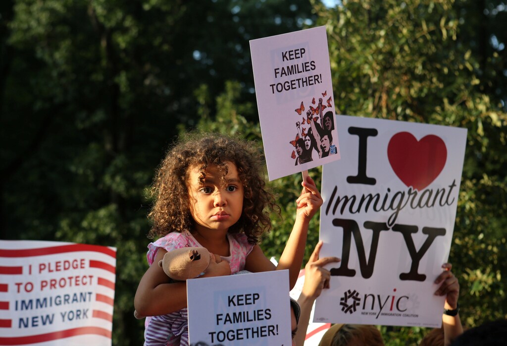 A girl sitting on the shoulders of her father holds a sign reading "Keep Families Together" at a protest against U.S. President Donald Trump's proposed end of the DACA program that protects immigrant children from deportation in New York City, U.S., August 30, 2017. REUTERS/Joe Penney - RC1F207E1690