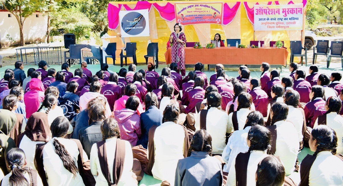 A speaker addressing a large group of students about the benefits and use of reusable sanitary pads during an educational workshop.
