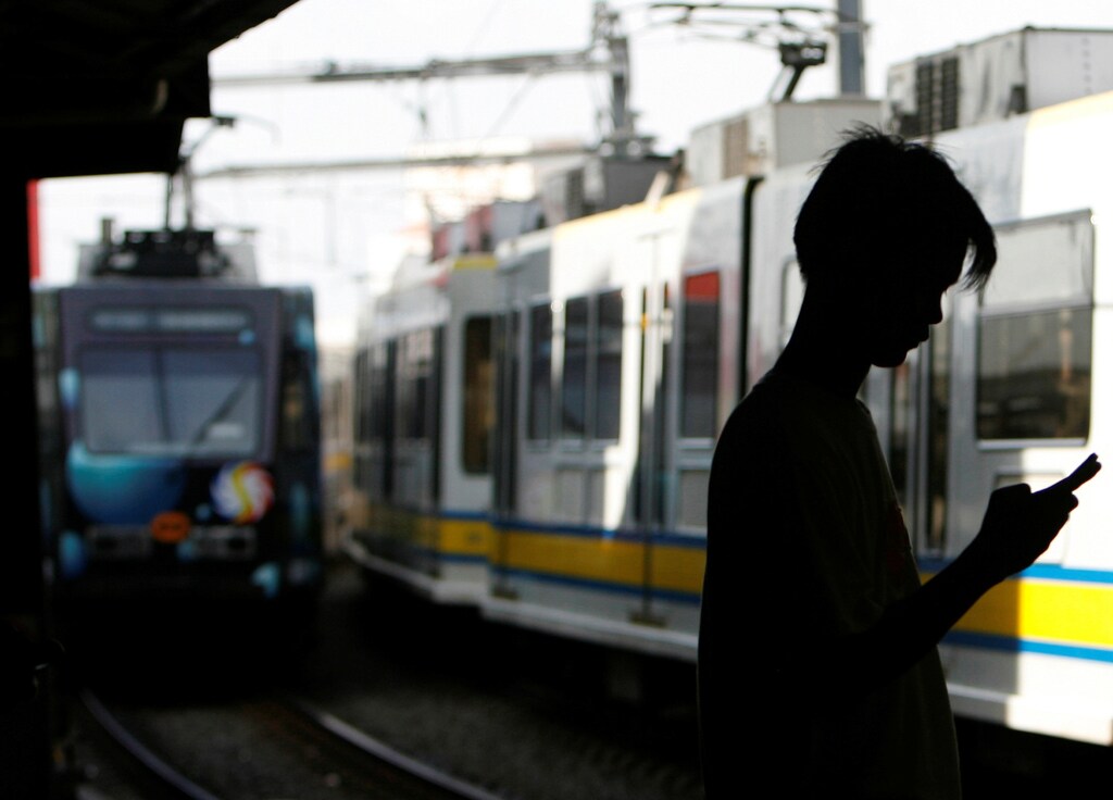 A commuter uses his mobile phone as a train arrives at a station in Pasay City, Metro Manila July 7, 2008.