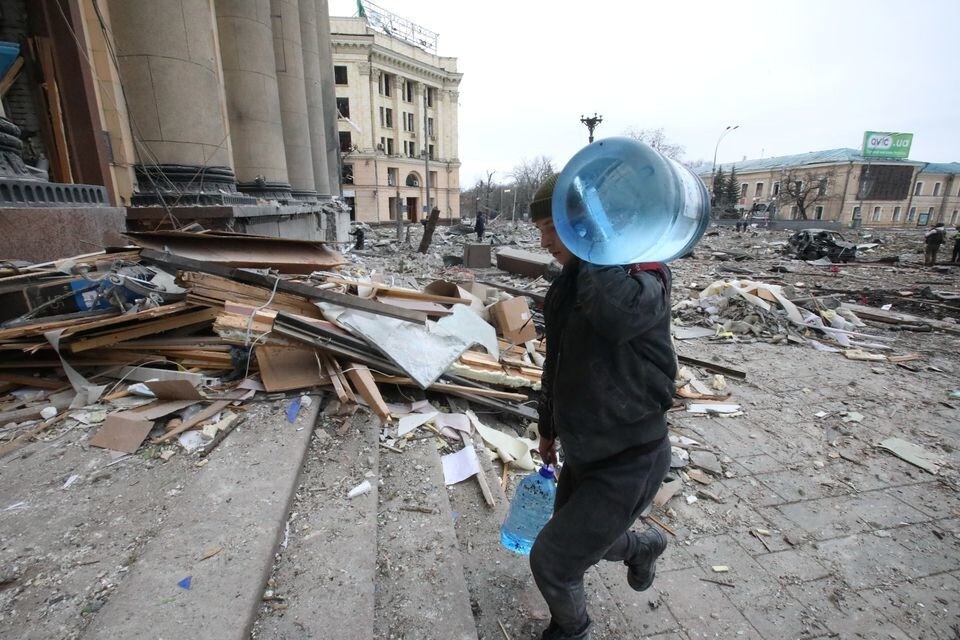 A man carries bottles with water outside the regional administration building, which city officials said was hit by a missile attack, in central Kharkiv, Ukraine, March 1, 2022