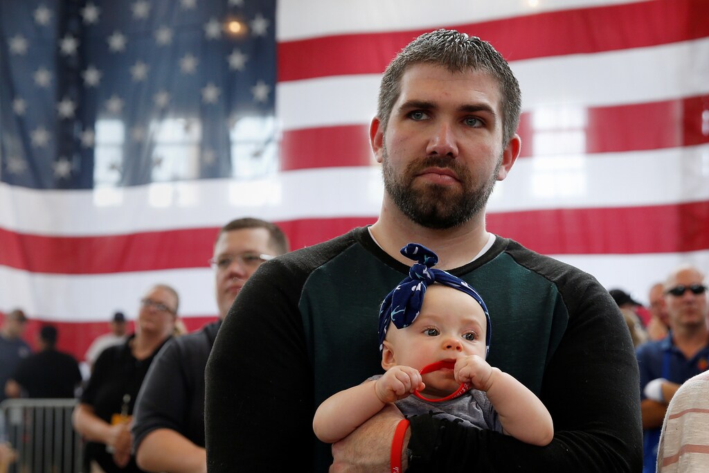 A man holds a baby as they wait for Republican nominee Donald Trump to speak at "Joni's Roast and Ride" in Des Moines, Iowa, U.S., August 27, 2016. REUTERS/Carlo Allegri - S1AETXYCXVAA