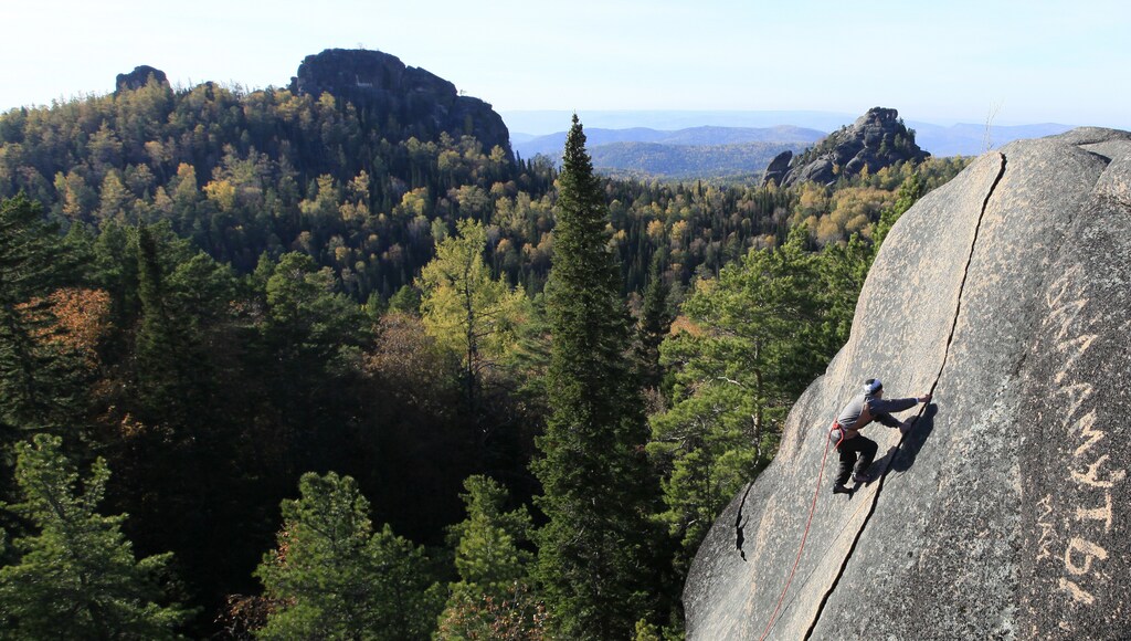 A tourist climbs up to reach the top of the rock named "The Fourth Stolb" (the Fourth Pillar) at the Stolby national nature reserve in the Siberian Taiga area outside the Russian city of Krasnoyarsk, October 2, 2013. Picturesque rocky blocks rising above the Taiga draw attention of tourists from all over Russia and abroad. Amateur rock-climbing became popular with local residents in the middle of the 19th century and since then more and more Siberians, who were later nicknamed "Stolbists", spent time in the Stolby (Pillars) natural reserve for outdoor sports and tourism. Picture taken October 2, 2013. REUTERS/Ilya Naymushin (RUSSIA - Tags: ENVIRONMENT TRAVEL) - RTR3FJQE