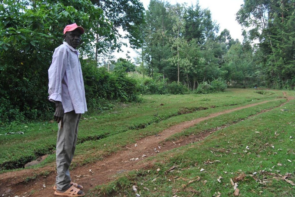 elder Julius Kosgei stands on what used to be an impassable river in Ainamoi village that is now dried up in Kenya's Kericho County