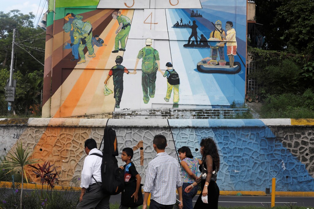 A family walks by a mural depicting the journey of central american migrants to the US in San Salvador, El Salvador, June 21, 2018. REUTERS/Jose Cabezas - RC1F3DC136C0