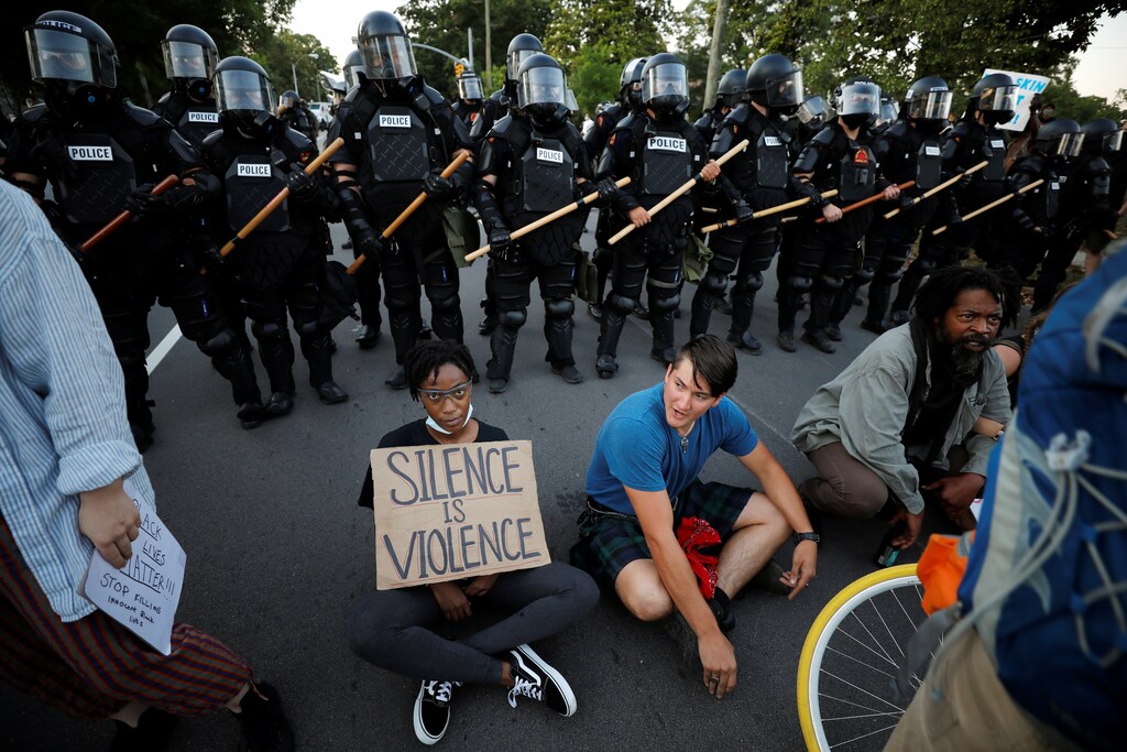Protesters sit with their backs to riot policemen during nationwide unrest following the death in Minneapolis police custody of George Floyd, in Raleigh, North Carolina, U.S. May 31, 2020. Picture taken May 31, 2020. REUTERS/Jonathan Drake - RC270H91Y6CW