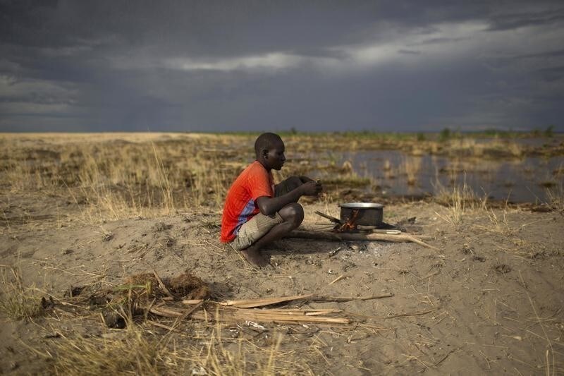 A Turkana man sits on the shore of Lake Turkana, some kilometres from Todonyang near the Kenya-Ethiopia border in northwestern Kenya October 12, 2013. The Turkana are traditionally nomadic pastoralists, but they have seen the pasture that they need to feed their herds suffer from recurring droughts and many have turned to fishing. However, Lake Turkana is overfished, and scarcity of food and pastureland is fuelling long-standing conflict with Ethiopian indigenous Dhaasanac, who have seen grazing grounds squeezed by large-scale government agricultural schemes in southern Ethiopia. The Dhaasanac now venture ever deeper into Kenyan territory in search of fish and grass, clashing with neighbours. Fighting between the communities has a long history, but the conflict has become ever more fatal as automatic weapons from other regional conflicts seep into the area. While the Turkana region is short of basics like grass and ground-water, it contains other resources including oil reserves and massive, newly discovered underground aquifers. Picture taken October 12, 2013.