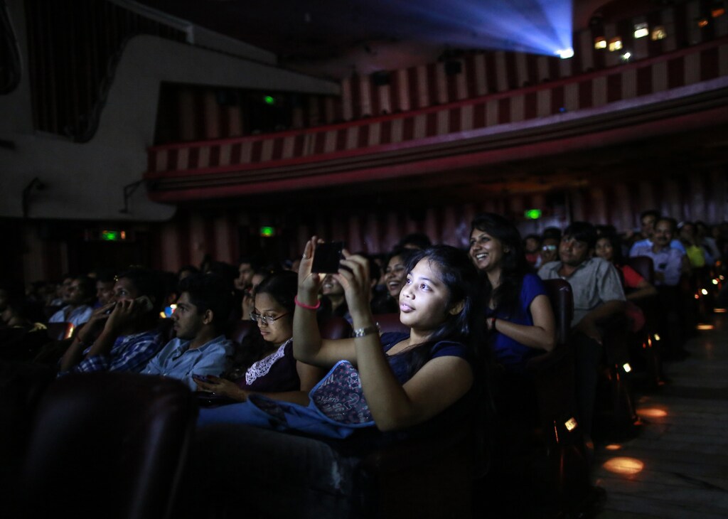A cinema goer takes a picture as others watch Bollywood movie "Dilwale Dulhania Le Jayenge" (The Big Hearted Will Take the Bride), starring actor Shah Rukh Khan, inside Maratha Mandir theatre in Mumbai December 12, 2014. The movie, released in October 1995, has set a record of completing 1000 weeks of continuous screening at a cinema, a feat unmatched by any other Bollywood movies. According to Manoj Desai, owner of the theatre, the movie, which is still being screened, enjoys at least 50 to 60 percent occupancy on weekdays and full house on weekends at his theatre.