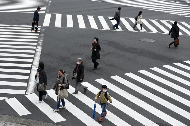 People cross a street in the Ginza shopping district in Tokyo, Japan, March 24, 2016. Japan's consumer inflation was flat in the year to February as low energy costs and weak consumption put a lid on price growth, keeping the central bank under pressure to top up stimulus even after easing policy less than two months ago. REUTERS/Thomas Peter - GF10000359724