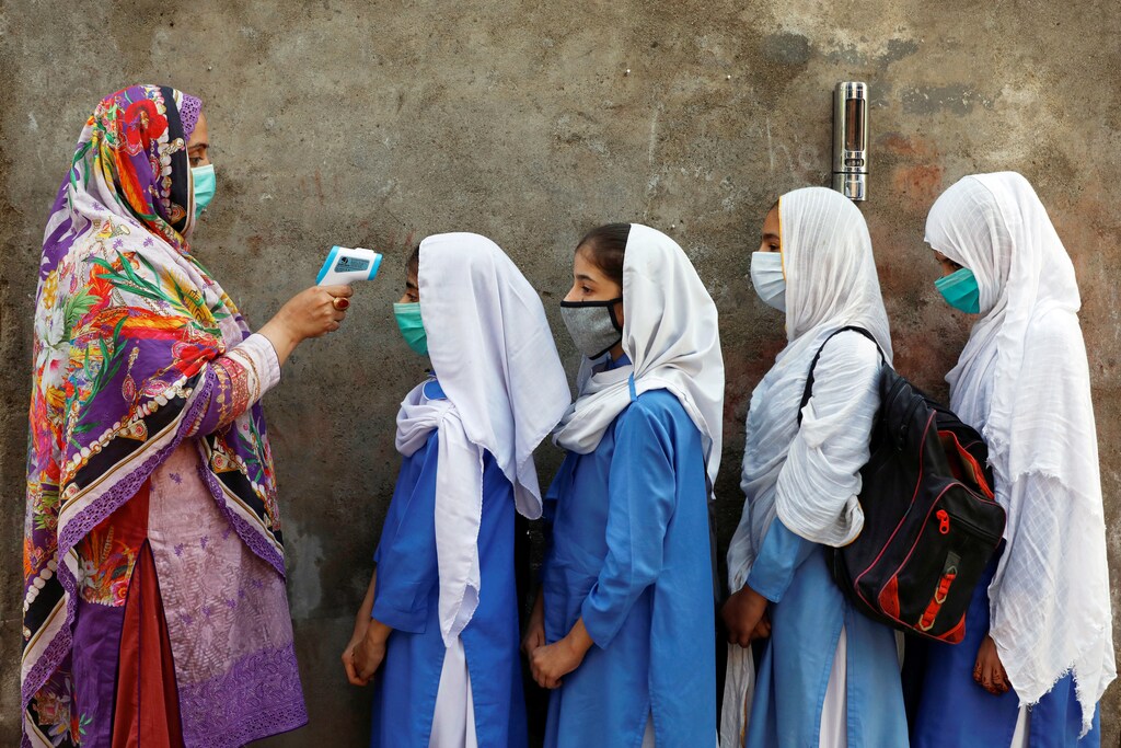 Students wear protective face masks as they have their temperature checked before entering a class, after the government allowed the reopening of schools from grade six to eight amid the coronavirus disease (COVID-19) pandemic, in Peshawar, Pakistan September 23, 2020. REUTERS/Fayaz Aziz TPX IMAGES OF THE DAY - RC2A4J9K9V05