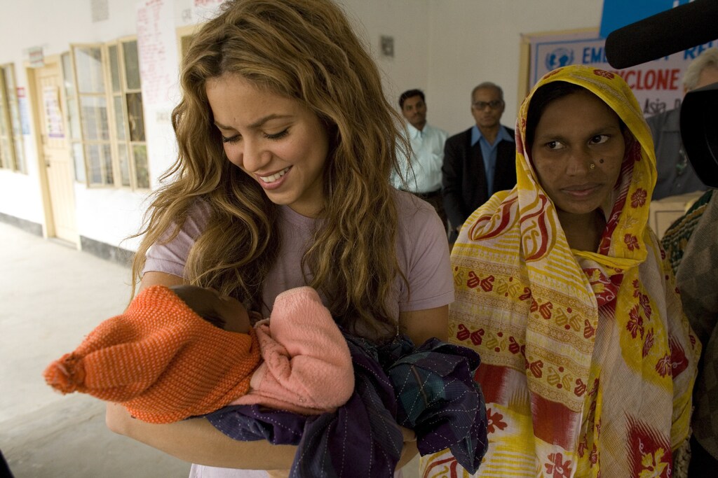 UNICEF Goodwill Ambassador Shakira holds a baby at an emergency relief distribution centre for people affected by Cyclone Sidr in Potuakhali District. The infant's mother stands nearby. Clothing and UNICEF family kits are distributed to children and women at the centre.From 17 to 19 December 2007, UNICEF Goodwill Ambassador and internationally acclaimed Colombian singer Shakira Mebarak visited Bangladesh to call attention to the situation of children affected by Cyclone Sidr, a Category 4 storm that struck the country on 15 November. More than 3,000 people were killed during the cyclone and an estimated 2.6 million people, half of them children, were left in need of life-saving assistance. In Patuakhali, one of the districts devastated by the storm, Shakira visited a UNICEF-supported child friendly space, one of 60 created to provide recreation and psychosocial support to children affected by the cyclone. She also took part in the distribution of UNICEF family kits to children and women. The kits contain 14 essential household items, such as utensils, a bucket, and soap, designed to assist families who have lost their homes. In the north-western district of Rajshahi, Shakira toured two primary schools in small villages and met with adolescent girls from the UNICEF-supported Adolescent Empowerment Project ('Kishori Abhiham'). She also visited a centre for girls who live or work on the streets, as well as a learning centre for child labourers.