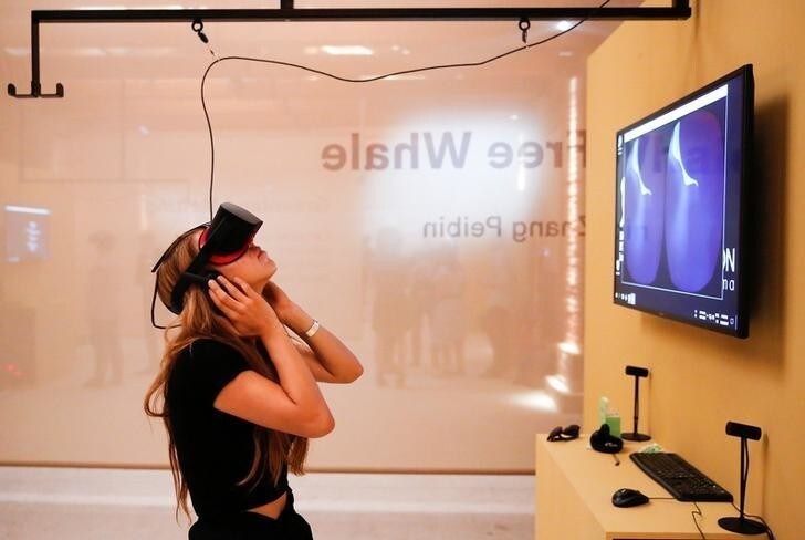 A woman tries on earphones and a headset used for virtual reality at the Venice Virtual Reality a competition during 74th Venice Film Festival in Venice, Italy August 29, 2017. REUTERS/Alessandro Bianchi