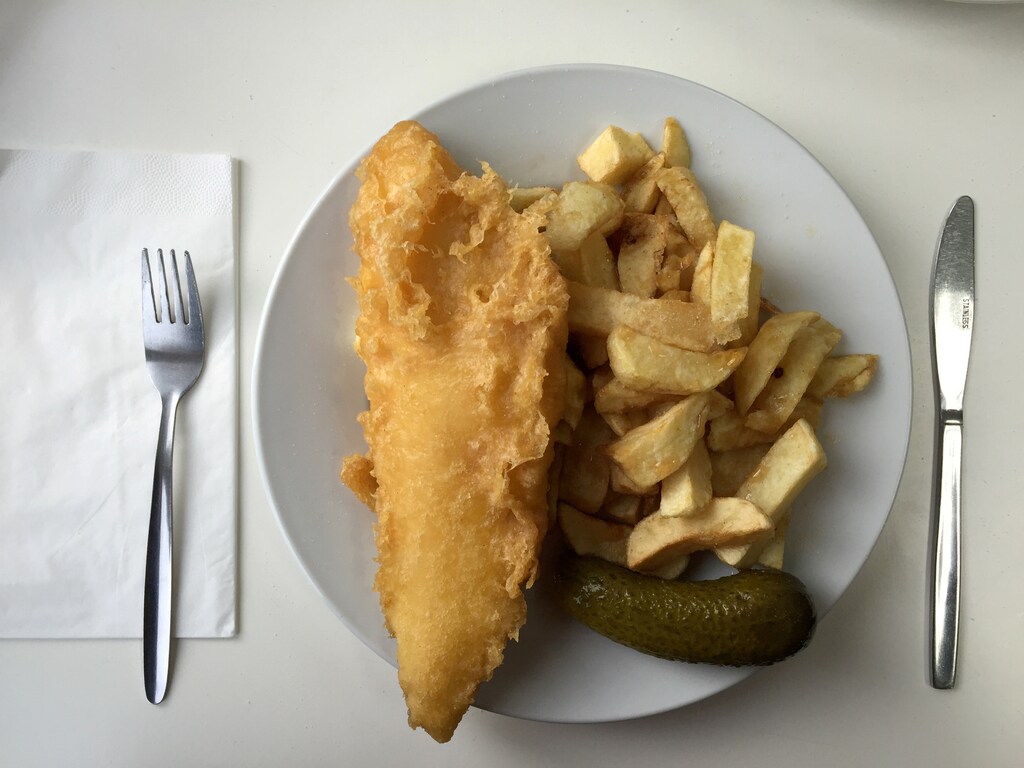 A plate of traditional fish and chips with a gherkin on a table in a seafront fish and chip shop in Brighton, Britain, December 22, 2015. REUTERS/Russell Boyce/File Photo - S1AETVMTPAAA