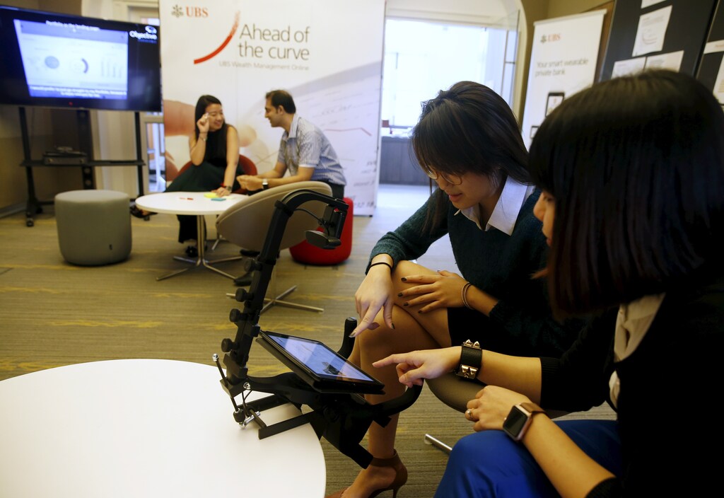 UBS employees demonstrate how their eye movements are being tracked to provide feedback on the interface design of a banking application on a tablet computer at their innovation center Evolve in Singapore March 17, 2016. REUTERS/Edgar Su - RTX29CS6