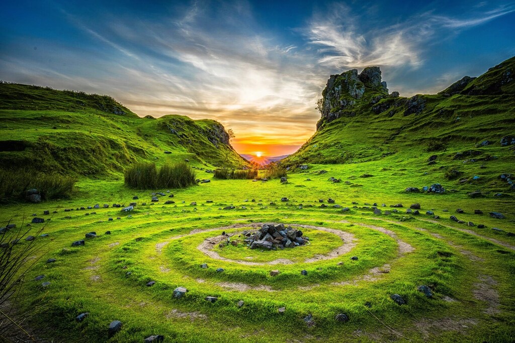 Campo de pastos verdes entre colinas durante la puesta de sol y marcas circulares en el suelo con piedras: El declive de la biodiversidad debe invertirse si queremos seguir siendo positivos para la naturaleza a partir de 2030.